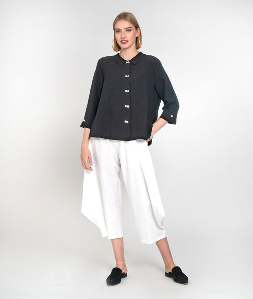 model in a white wide leg cropped pant with a charcoal button down boxy blouse with a 3/4 sleeves and a twin button detail