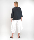 model in a white wide leg cropped pant with a charcoal button down boxy blouse with a 3/4 sleeves and a twin button detail