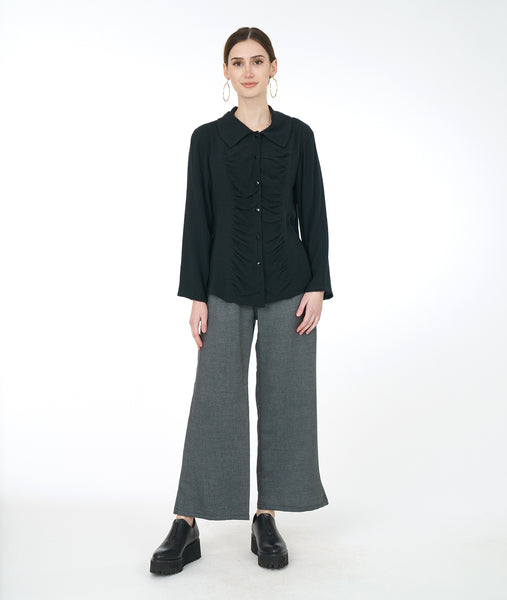 model in a wide leg grey pant with a black button down blouse with a gathered panel along the front center of the bodice