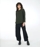 model in a distressed black pant with a matching olive green top with long sleeves and a small  triangular placket with a single button at the neckline