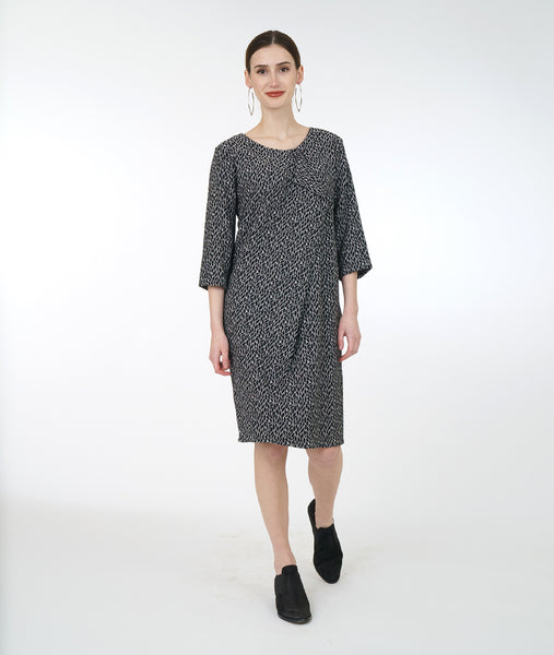 model in a black and white leaf print shift dress with an asymmetrical flounce at the neckline and 3/4 sleeves