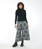 model in a wide leg grey patterned pant, with a black mock turtleneck top
