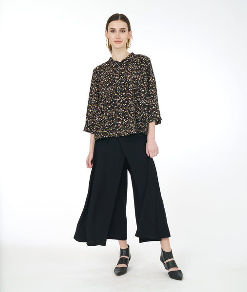 Model in a wide leg black pant with a black terrazzo print blouse with 3/4 sleeves and a twin button