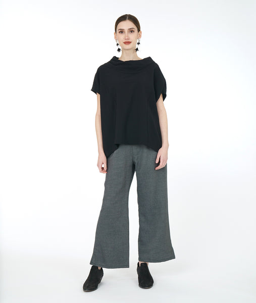 model in a wide leg grey pant with a textured black boxy top with a cowl neckline and princess seams