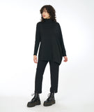 model in a slim black pant and asymmetrical black top with a mock turtle neck and one full cocoon sleeve