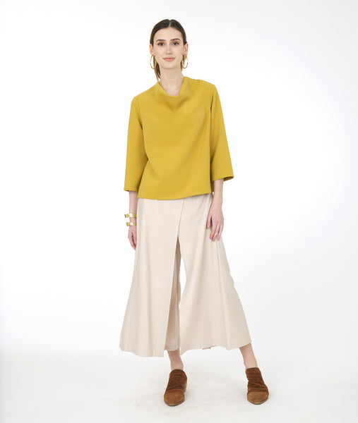 model in a wide leg ivory pant with a gold cowl neck top