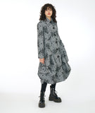 model in a grey and black print coat with large pleats at the bottom hips