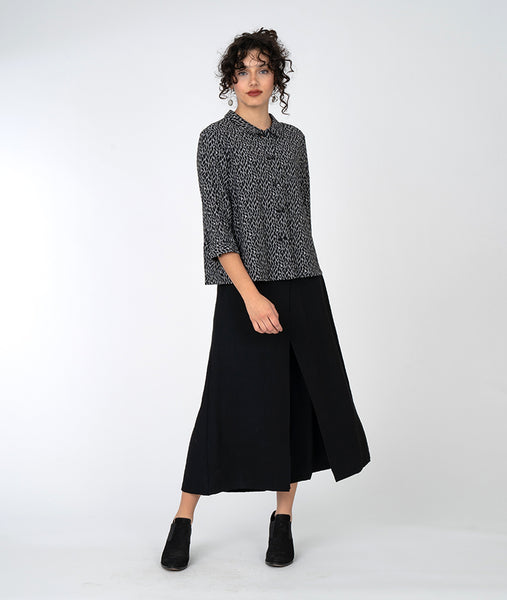 model in a wide leg black pant with a black and white leaf print button down blouse with a 3/4 sleeve