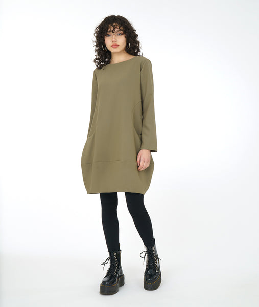 model in black leggins with a sage green tunic with long sleeves and a curved seam at either side with set in pockets