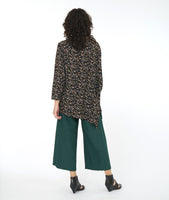model in a wide leg forrest green pant with a black terrazzo print top. Top is asymmetrical with a drape and cocoon sleeve on one side only
