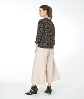 Model in a wide leg ivory pant with a black terrazzo print blouse with 3/4 sleeves and a twin button
