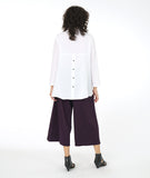 model in a white button down blouse with a lower hem in the back, worn with an eggplant color wide leg pant with an overlapping panel on the front