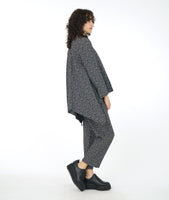 model in a black and white leaf print straight leg pant, worn with a matching tunic with long sleeves, a v-neck and a low double point drape in the back 