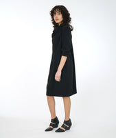model in a black long sleeve shift dress with a cowl neck