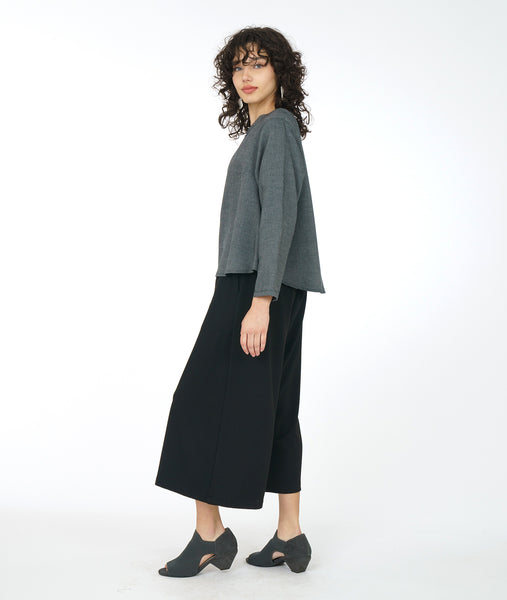 model in a boxy grey top with a wide leg black cropped pant with pockets