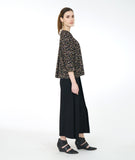 Model in a wide leg black pant with a black terrazzo print blouse with 3/4 sleeves and a twin button