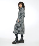 model in a grey and black print coat with large pleats at the bottom hips
