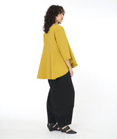 model in a wide leg black pant worn with a gold top with a full flowing body and 3/4 sleeves