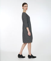 model in a black and white leaf print shift dress with an asymmetrical flounce at the neckline and 3/4 sleeves