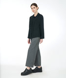 model in a wide leg grey pant with a black button down blouse with a gathered panel along the front center of the bodice