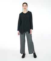 model in a wide leg grey pant with a black button down blouse with a hankerchief hem