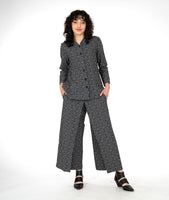 model in a leaf print wide leg pant with an overlap in the front center waist, worn with a matching button down blouse with long sleeves and a mandarin style collar
