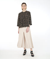 Model in a wide leg ivory pant with a black terrazzo print blouse with 3/4 sleeves and a twin button