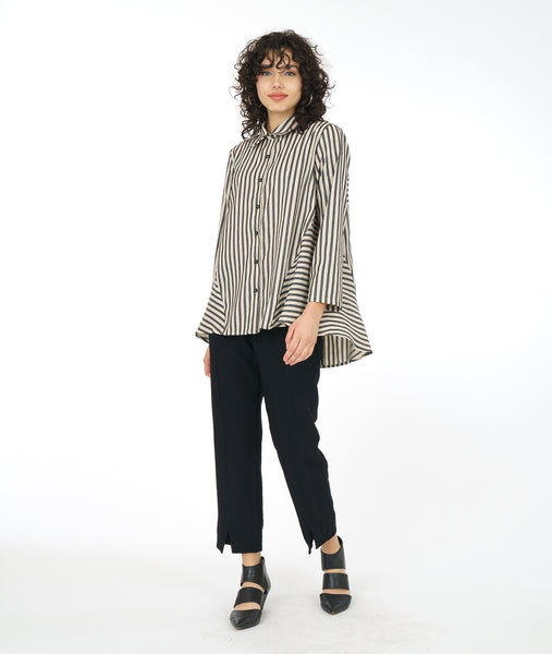 model in a black and taupe striped top with a full and flowy back panel, worn with a slim black pant