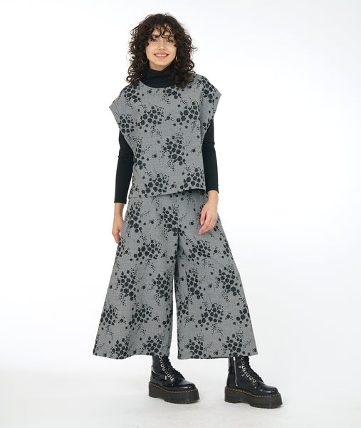 model in a wide leg grey patterned pant with a matching vest over a black mock turtleneck