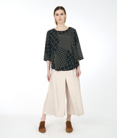 model in a wide leg ivory pant with a black and ivory grid print top with a flowing hi-lo body