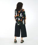 model in a wide leg black pant with a multi color print top with a flowing hi-lo body