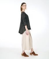model in a wide leg ivory pant with a black and ivory grid print top with a flowing hi-lo body