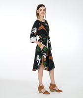 model in a black multi color dress with a wide cuff at a 3/4 sleeve, kimono style sleeves and a tie at the waist that can be worn around the waist or just in front