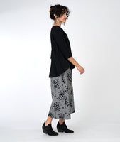 model in a wide leg grey and black print pant with a black pull over top with 3/4 sleeves and a high-low hem