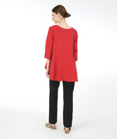model in a slim black pant with a red pull over top with 3/4 sleeves and a high-low hem