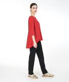 model in a slim black pant with a red pull over top with 3/4 sleeves and a high-low hem