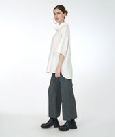 model in a wide leg grey pant with a white oversized top with a cowl neck and drop shoulders