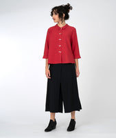 model in a wide leg black pant with a red button down blouse with a twin button detail and a 3/4 sleeve