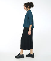 model in a wide leg black pant with a teal button down blouse with a twin button detail and a 3/4 sleeve