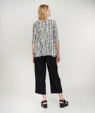 model in a black crop pant with a white tee with black polka dots, a scoop neckline, hankerchief hem and a 3/4 sleeve