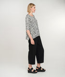 model in a black crop pant with a white tee with black polka dots, a scoop neckline, hankerchief hem and a 3/4 sleeve