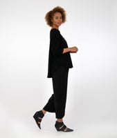 model in a black pant and top, with a high low hem