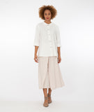 model in a wide leg tan pant with a long button down blouse in white
