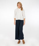 model in a wide leg navy blue pant with a white button down blouse with a twin button detail and a 3/4 sleeve