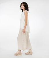 model in a long white tank, worn with a wide leg oatmeal color pant with a split at the side seams