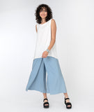 model in a wide leg blue pant with an overlay flap, with a white tank