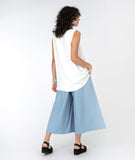 model in a wide leg blue pant with an overlay flap, with a white tank