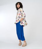 model in an electric blue pant with a floral print pullover top with a high low hemline