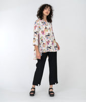 model in a slim black pant with a floral print button down blouse with a full flowing back