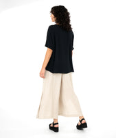 model in a black tee with a wide leg oatmeal color pant with a split at either side seam